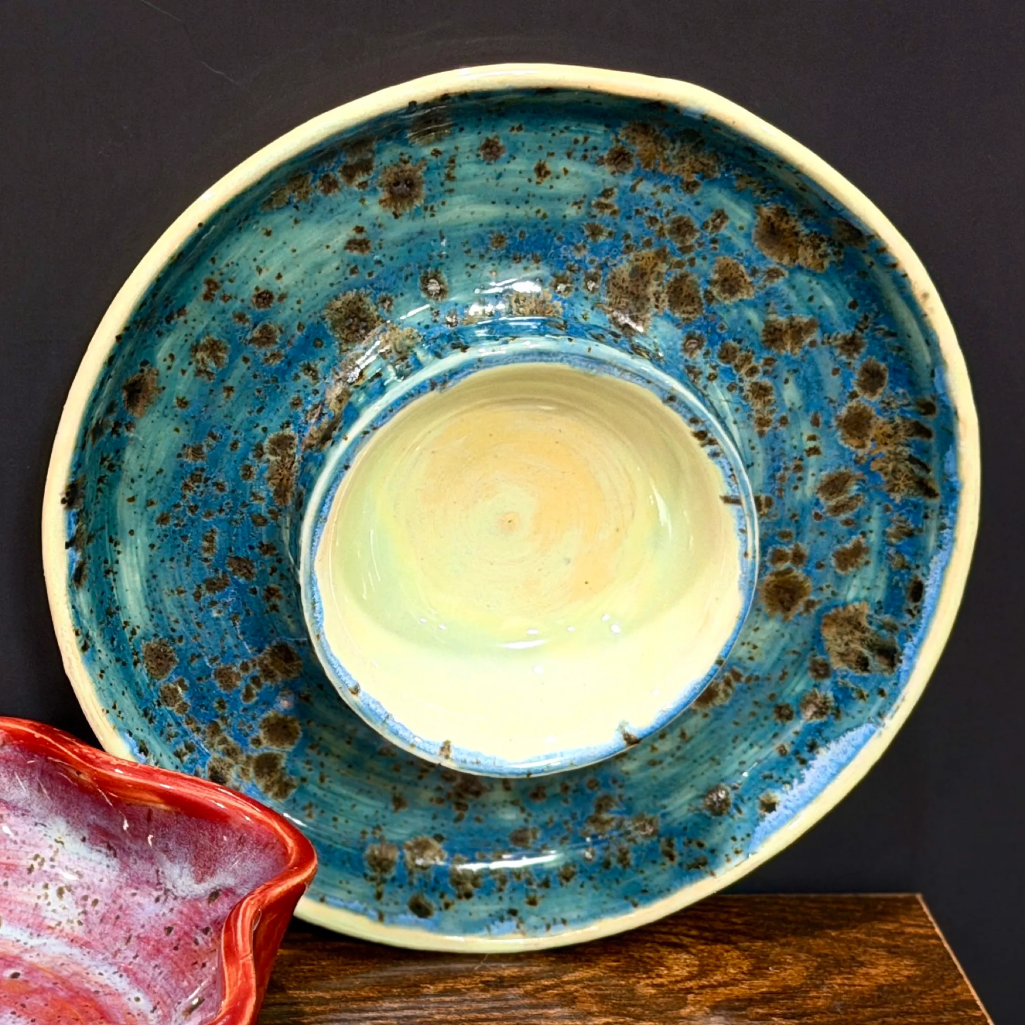 A wide round platter in speckled ocean blue with a raised cream-colored bowl in the center for dip.