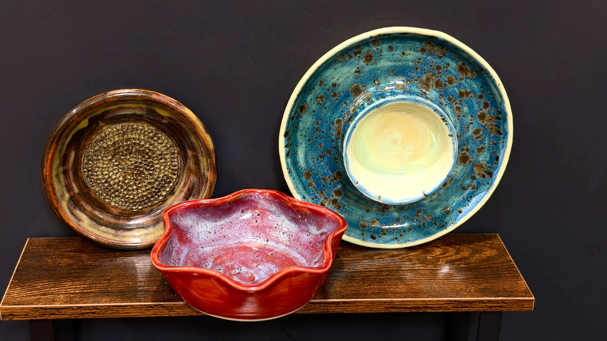 The garlic grater plate, star bowl, and chip and dip bowl together on a wooden shelf.